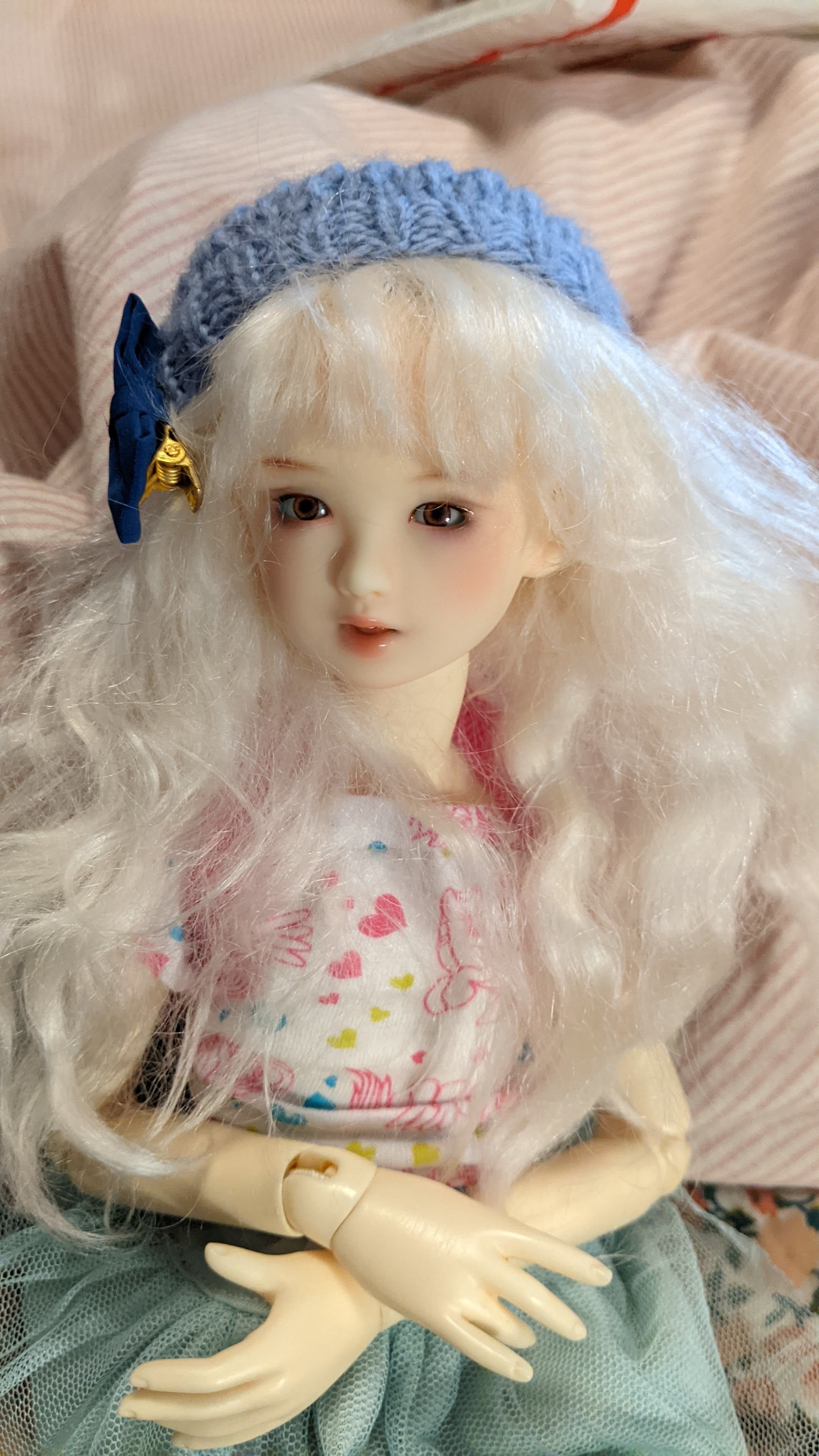a photo of a girl doll looking up at the viewer. she is white and has white hair. she is wearing a beret.
